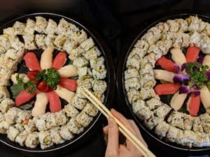 Sushi platter featuring assorted rolls with fresh vegetables and seafood, garnished with colorful fl.