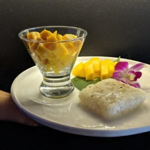 Thai Mango Sticky Rice dessert with fresh mango and coconut, served with orchid flower.