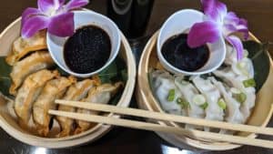 Dumplings with soy sauce and orchids at Thai Lotus Restaurant, showcasing authentic Thai cuisine.