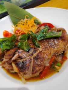 Authentic Thai Lotus Restaurant grilled fish with fresh herbs and vegetables.